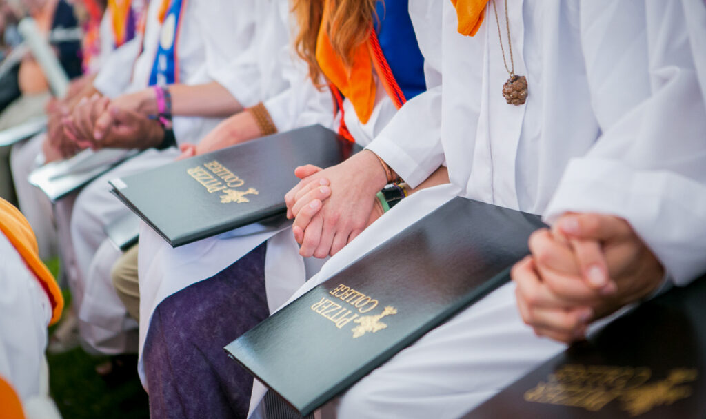 people holding hands with Pitzer diplomas
