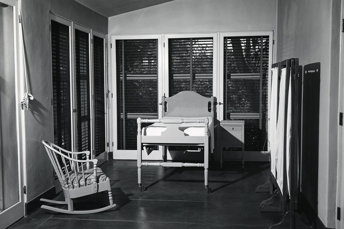 Archive photo of one of the sun rooms in the infirmary with a bed, a chair and a privacy curtain.