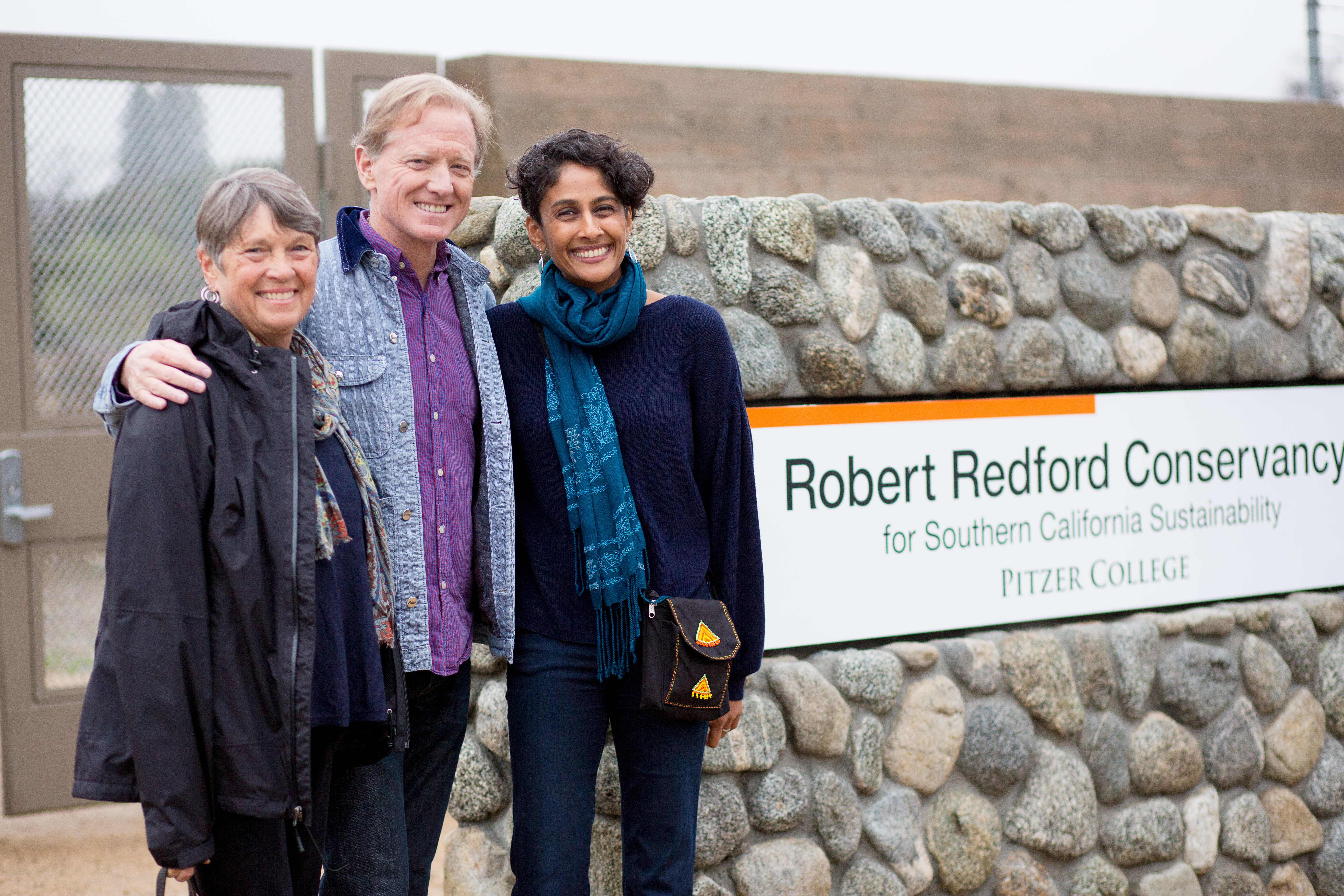 Trustee and donor Susan Pritzker, director and filmmaker James Redford and Conservancy Director Professor Brinda Sarathy by the Redford Conservancy sign on Foothill Boulevard in March 2018.