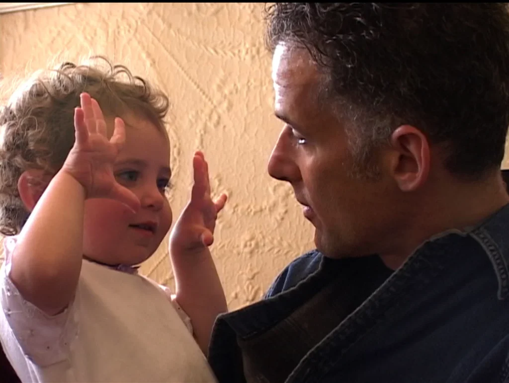 Ella Rosenblatt at two years old holds up both her hands as she looks at her father Jay Rosenblatt.