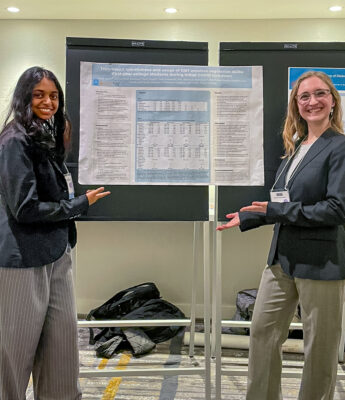 Pratya Poosala and Sarah Mann stand in front of a poster documenting the research project titled Trait-based mindfulness and usage of DBT emotion regulation skills: First-year college students during initial Covid lockdown.