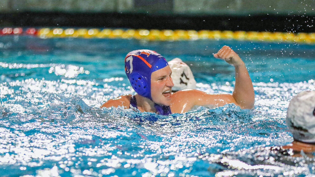 A Pomona-Pitzer women’s water polo player raises a fist and shouts triumphantly in the pool.