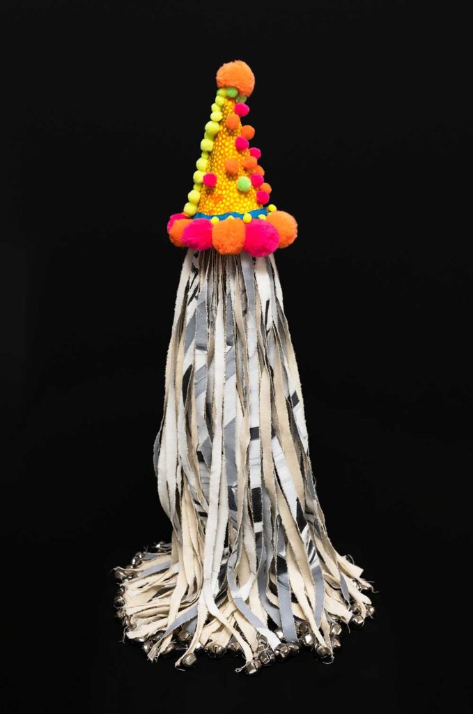 Steelink's artistic piece Spirit Painting No. 1. Shredded acrylic painting on canvas topped with an orange, yellow, and pink cone decorated like a party hat with pom-poms.