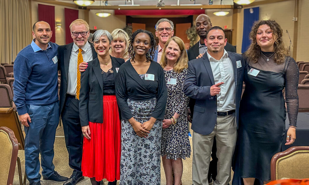Pitzer alumni and staff stand with Taeya Boi-Doku ’24 in the center for a group photo at the Napier Award celebration ceremony.