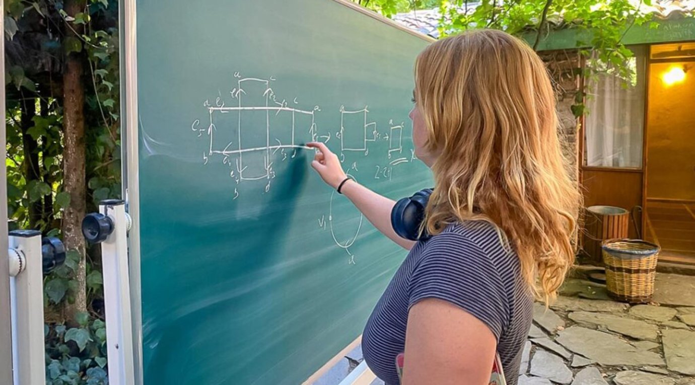 a math student solves a problem on a blackboard