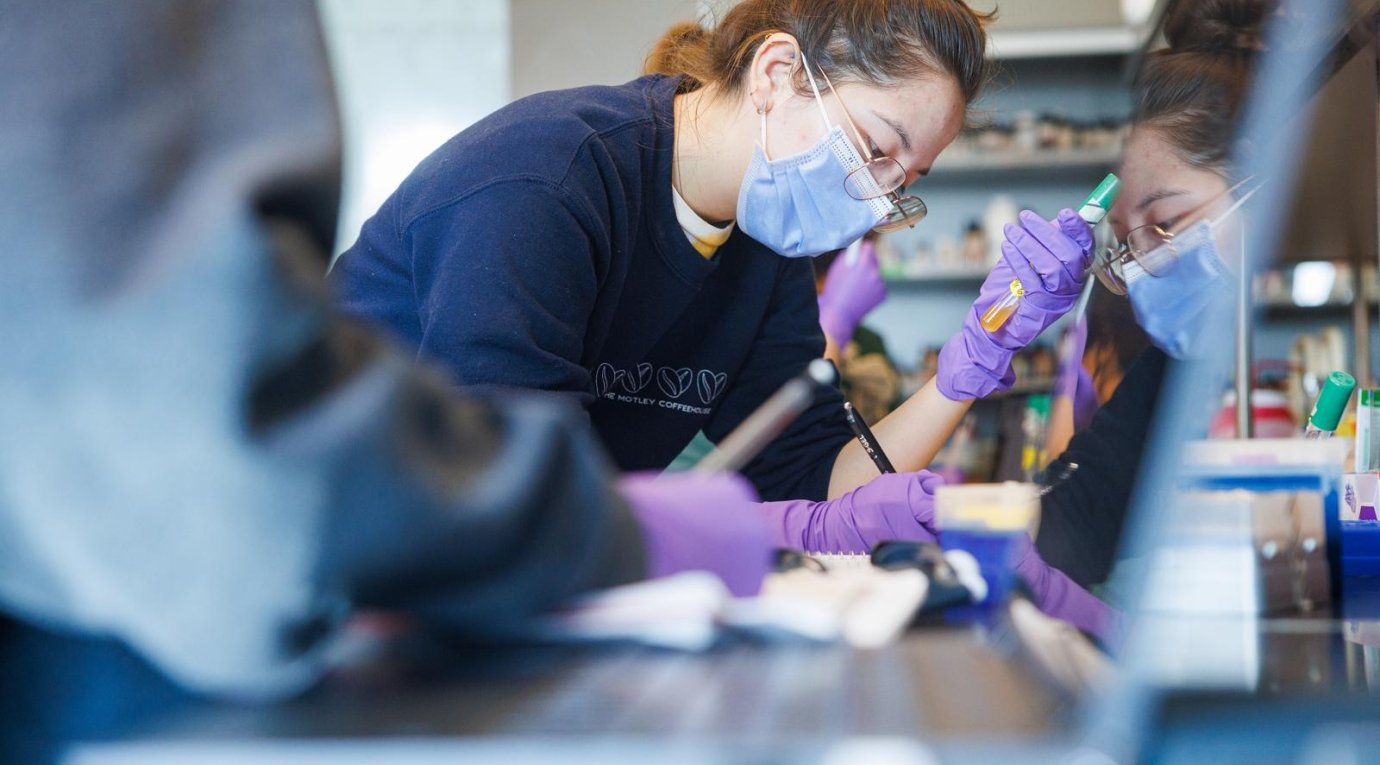 A Pitzer student writes down some data while holding a test tube