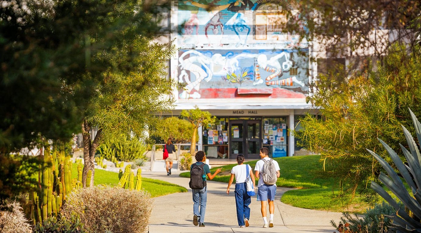 three students walk towards mead hall