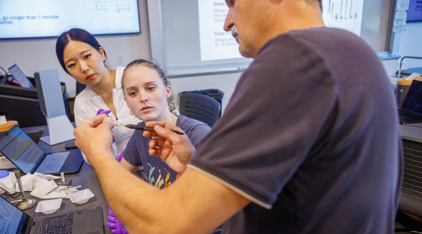 A biology professor performs a demonstration for two students