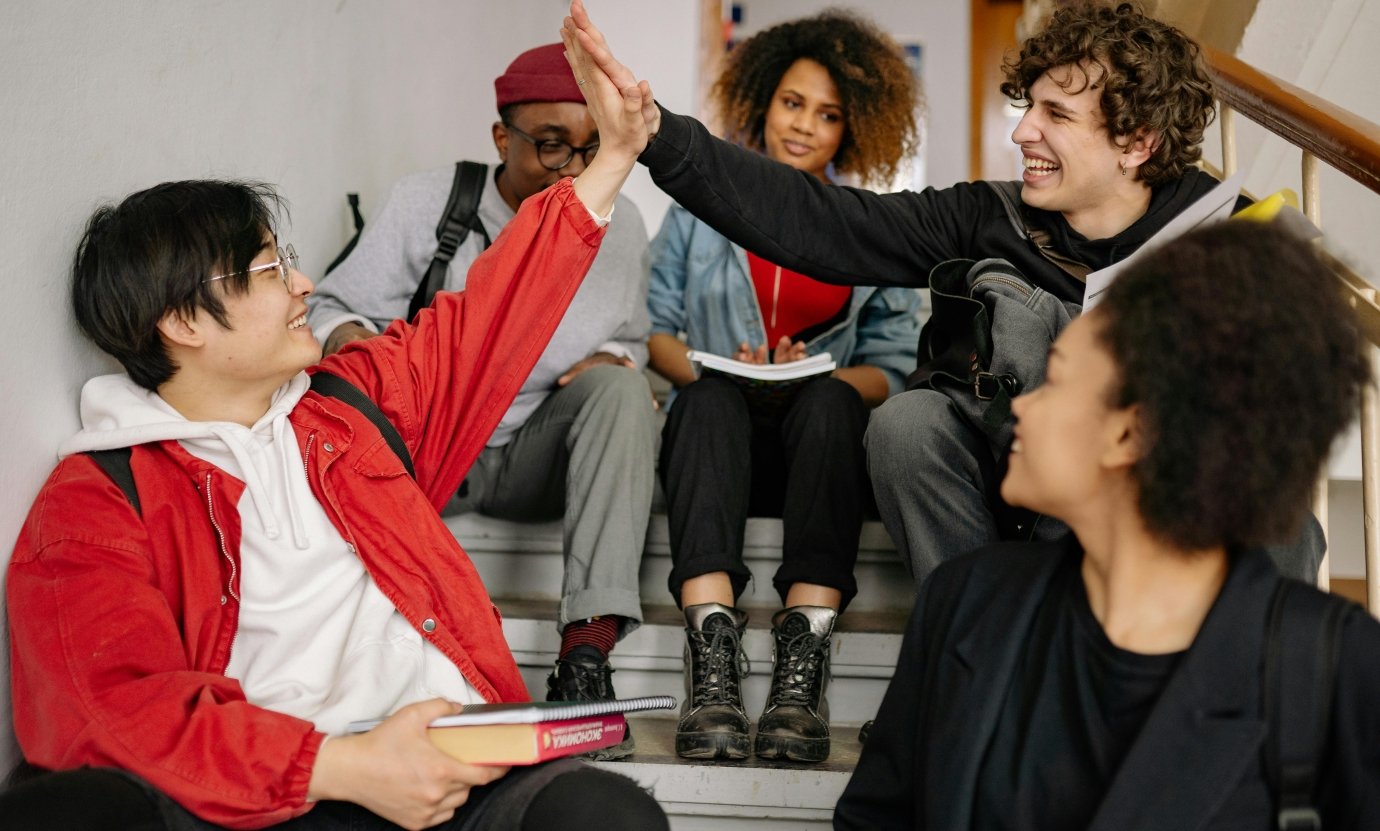 students sitting on the stairs and two giving high five