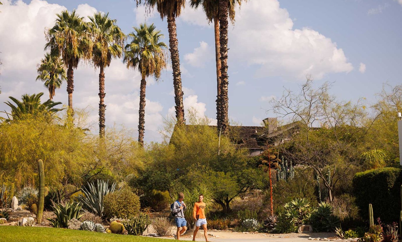 two student walk in front of the grove house  on a sunny day