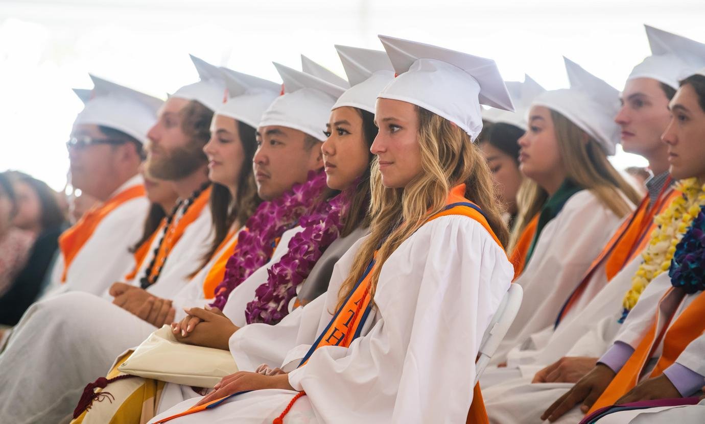 graduates sit in chair facing the stage in the pitzer commencement tent