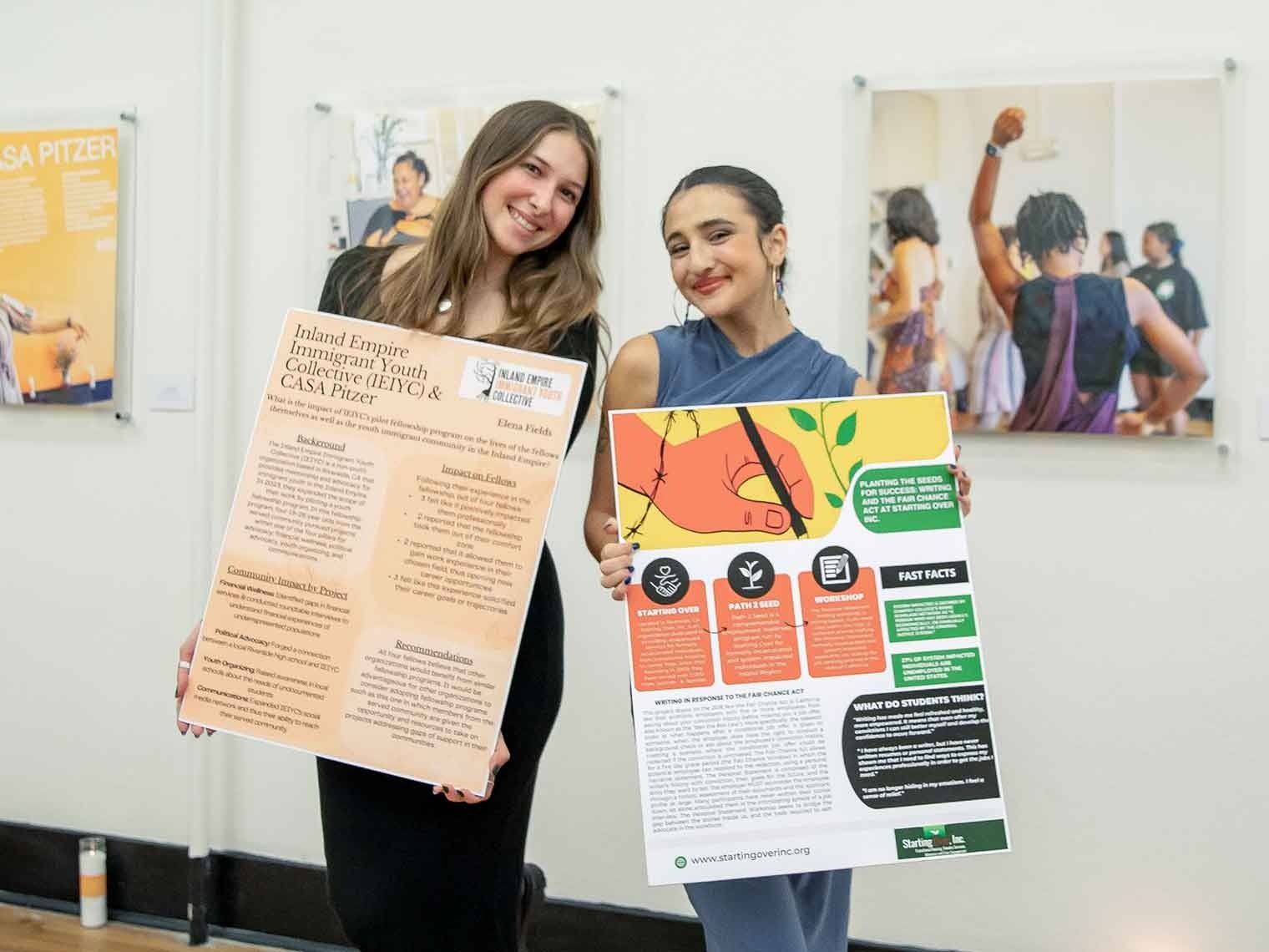 two casa students pose with their posters presentations