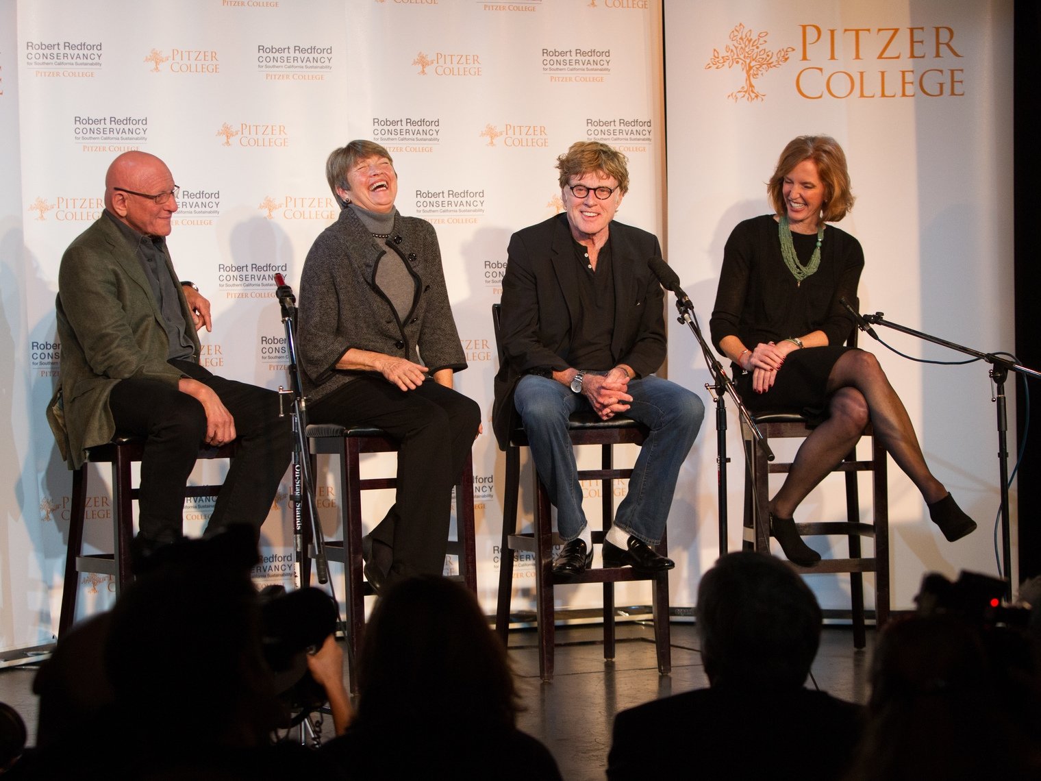 Robert Redford sits on a stage with Pitzer College president Laura Trombley and two other guests. 