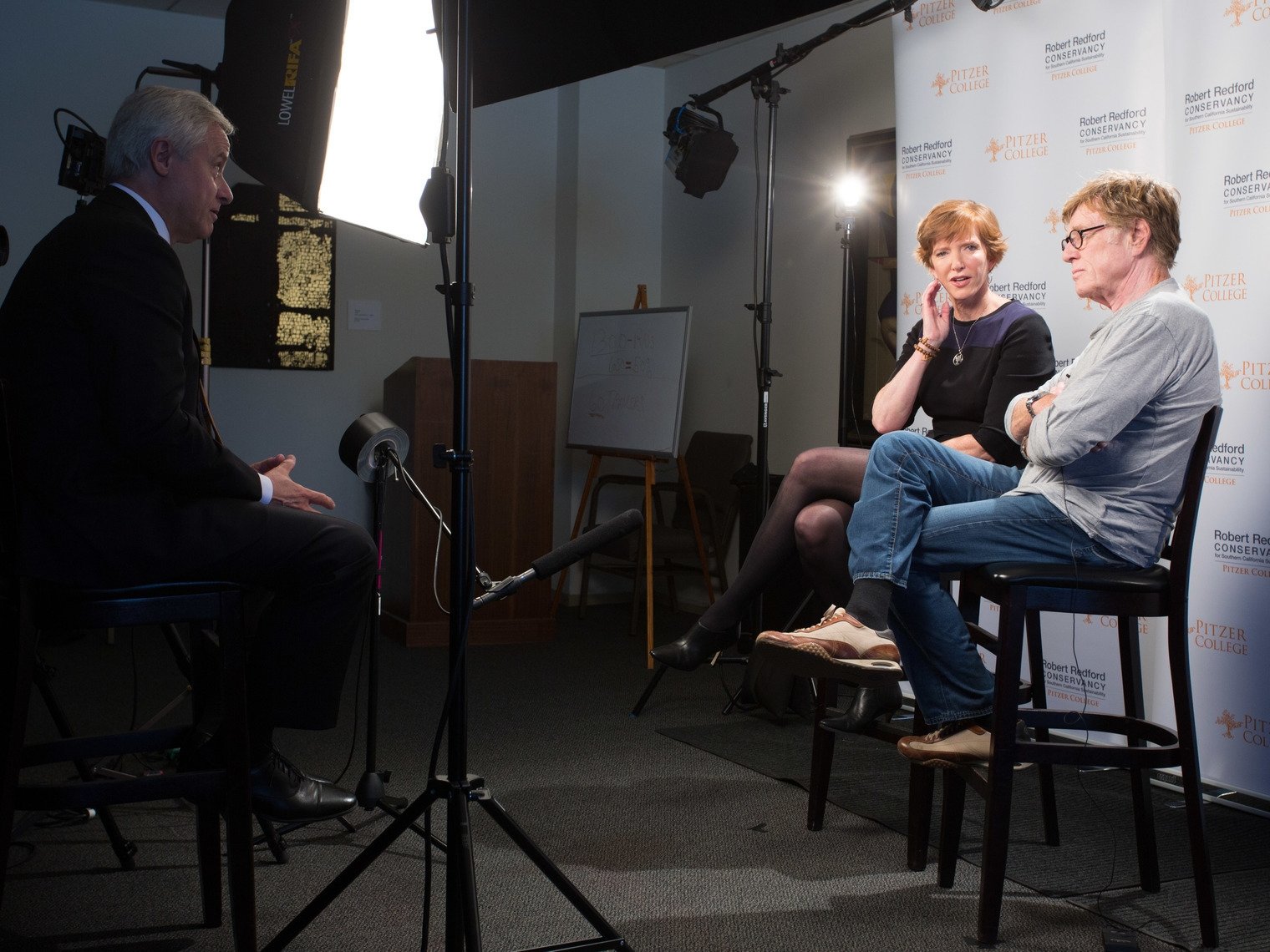 Pitzer College president Laura Trombley and Robert Redford are interviewed in front of a Pitzer College branded backdrop
