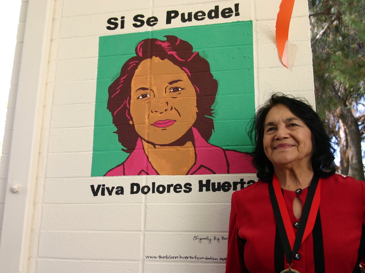 Dolores Huerta poses with her mural at Pitzer College