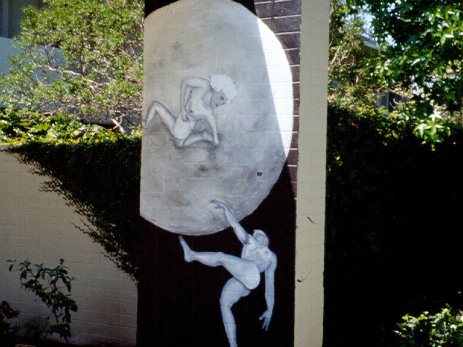 a black and white mural of moon and two human figures