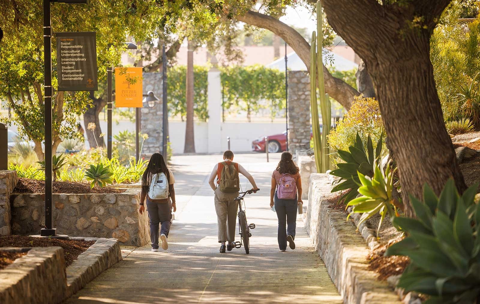 three students walk down pitzer walk toward pitzer gate