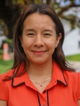 Closeup of Alma Bezares Calderon, who has straight brown hair and wears an orange collared top.