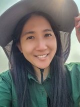 Closeup of Jo Ann Wang, who has long straight black hair and weras a green collared shirt and a wide-brimmed white hat.