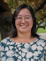 Closeup of Lisa Yin Han, who has shoulder-length straight black hair and wears glasses and a blue top with white floral print.