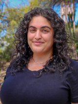 Tahereh Aghdasifar has long curly dark hair and wears a black top while standing outdoors.