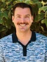 Man with blue collar shirt and brown short hair.