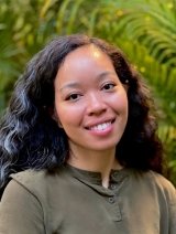 Woman in green top with black curly hair.