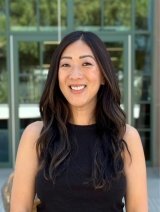 Woman wearing black top with black wavy hair.