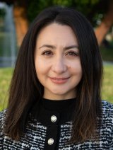 Woman with dark brown hair wearing black and white coat. 
