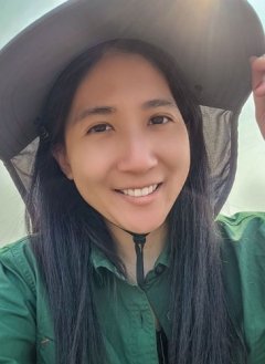 Closeup of Jo Ann Wang, who has long straight black hair and weras a green collared shirt and a wide-brimmed white hat.