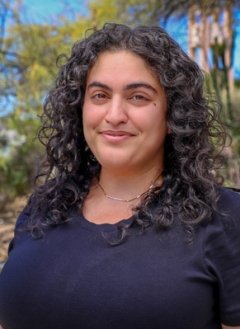 Tahereh Aghdasifar has long curly dark hair and wears a black top while standing outdoors.