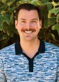 Man with blue collar shirt and brown short hair.