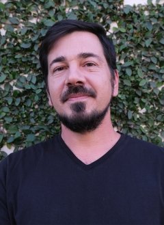 Man in black top with short black hair and beard.