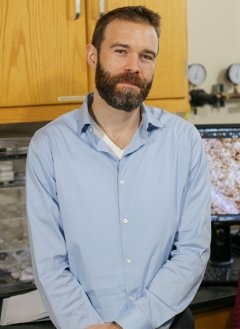 Man in blue button up with short brown hair and beard.