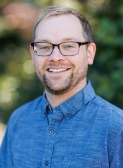 Man in blue shirt wearing glasses with blonde short hair.