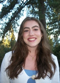 Woman wearing white cardigan with long brown hair.
