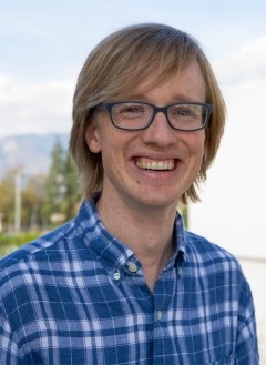 Man in blue striped shirt wearing glasses with short blonde hair.