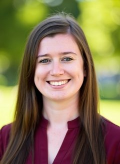 Woman wearing maroon blouse with long brown hair.