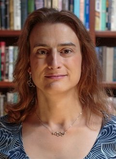 Woman in short brown hair wearing blue top.