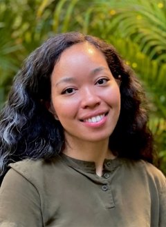 Woman in green top with black curly hair.