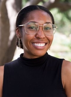 Woman in black top wearing glasses in short brown hair.