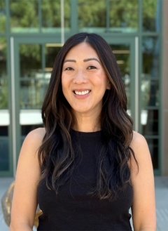Woman wearing black top with black wavy hair.