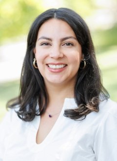 Woman wearing white top with short black hair.