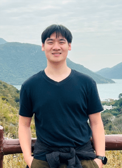 Man wearing black shirt with short black hair posing in front of mountain view point.