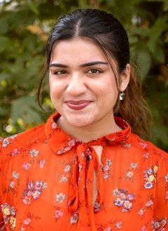 a student with long brown hair pulled back into a pony tail wears a orange blouse with a flower print