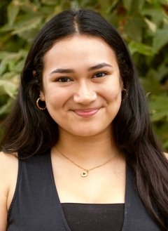 head shot of Brenda Aguilar standing in front of an outdoor plant
