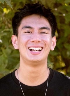 head shot of Kian Ayno standing in front of outdoor greenery