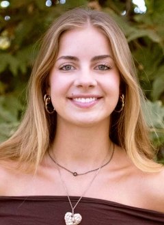 head shot of Sadie Blain standing in front of outdoor greenery