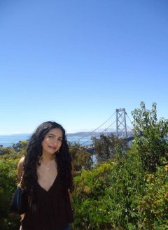 A girl standing in front of a view of the golden gate bridge