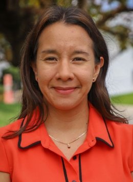 Closeup of Alma Bezares Calderon, who has straight brown hair and wears an orange collared top.
